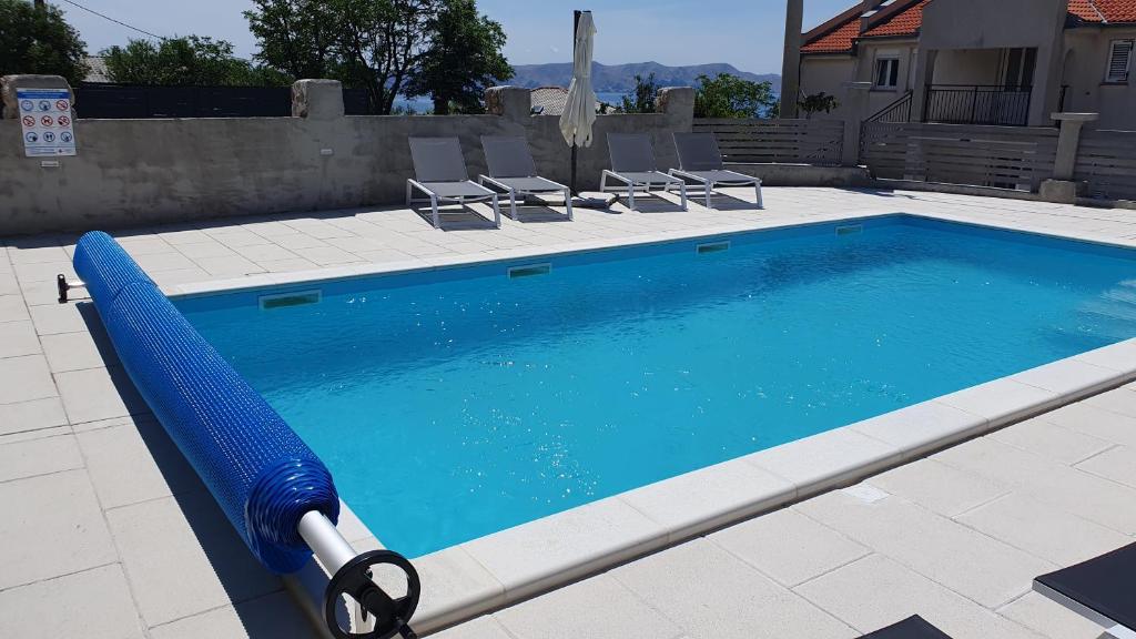 a large swimming pool with chairs in a backyard at Apartmani Naomi&Leo in Senj