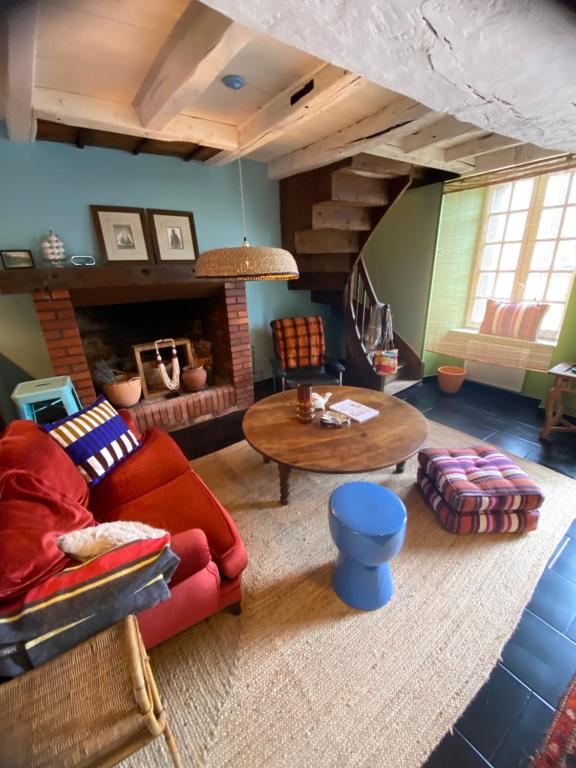 a living room with a red couch and a table at la petite maison Normandie in Saint-Cyr-du-Bailleul