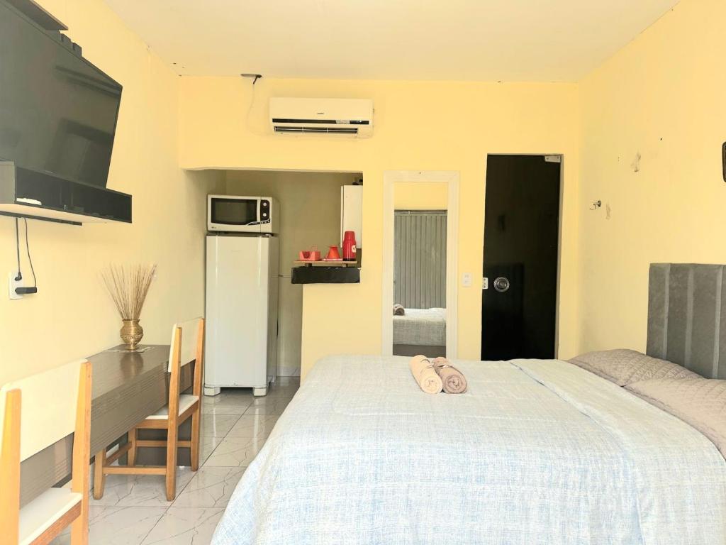a bedroom with a bed and a table and a kitchen at Capim dourado privativo a minutos do aeroporto e rodoviária in Palmas