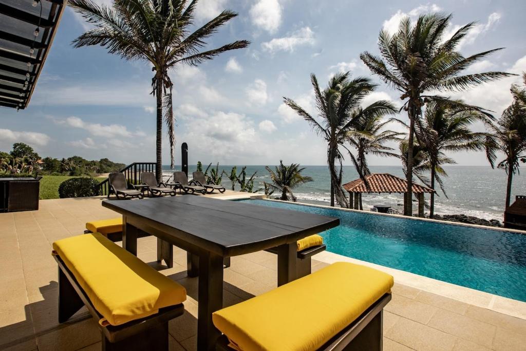 un patio con mesa y sillas junto a una piscina en Super Private Beachfront 3BR Villa with Infinity Pool Andromeda Pedasi en Pedasí Town