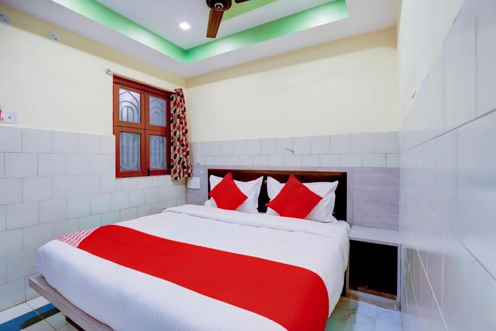 1 dormitorio con 1 cama con almohadas rojas y blancas en OYO Sam Guest House en Chennai