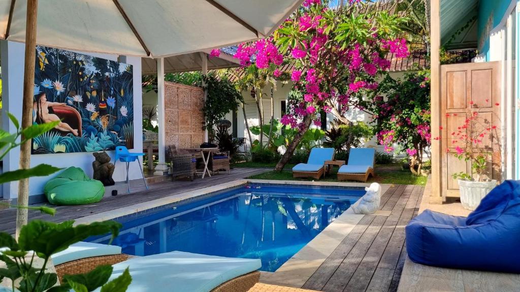 a swimming pool with chairs and an umbrella at Starling villas in Sanur