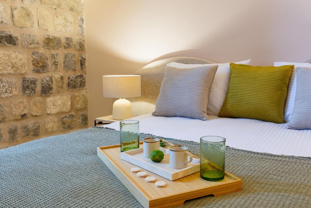 a bedroom with a bed with a tray of water and glasses at Boutique hotel Ruzmarin SPA & Garden by Aycon in Budva