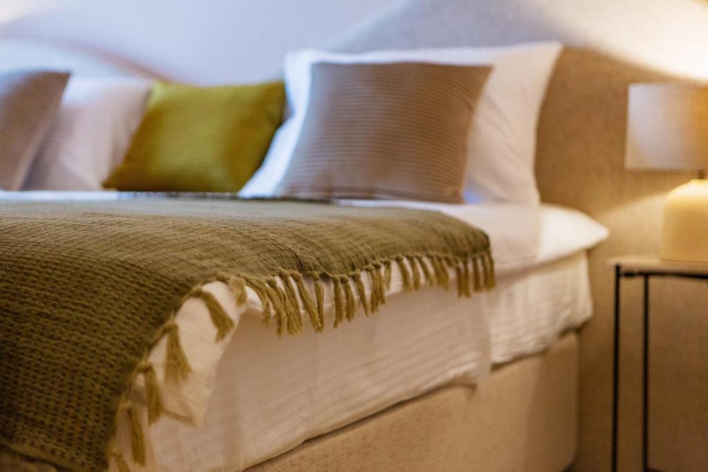 a bed with pillows and a blanket on it at Boutique hotel Ruzmarin SPA & Garden by Aycon in Budva