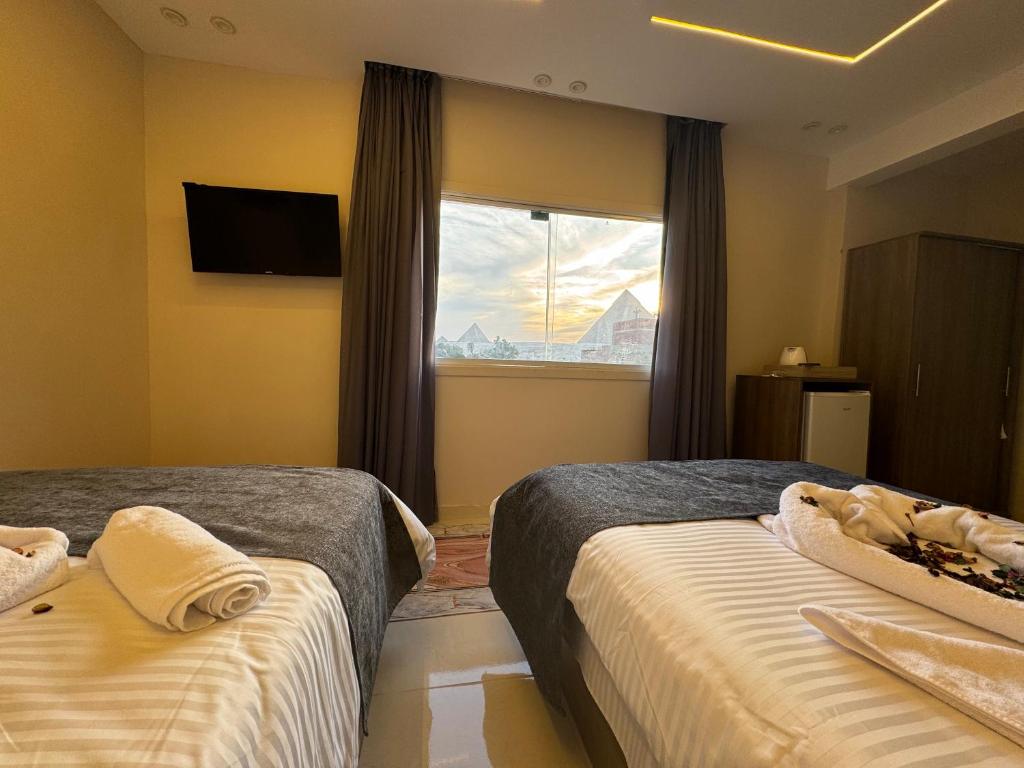 a hotel room with two beds and a window at Dima Pyramids View in Cairo