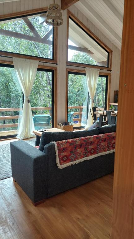 sala de estar con sofá y ventanas grandes en Tres Bosques en Pucón