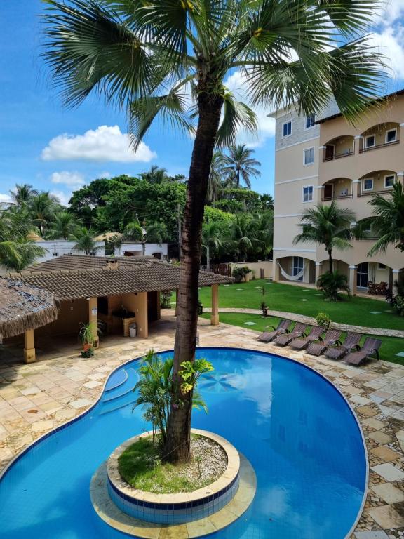 un palmier en face d'un hôtel avec piscine dans l'établissement Cumbuco Residence #203, à Caucaia