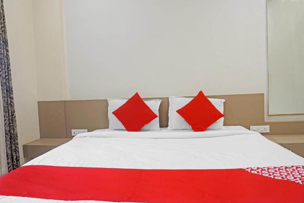 a bed with red and white pillows on it at OYO Flagship 84218 Hotel Bankar House in Sonai