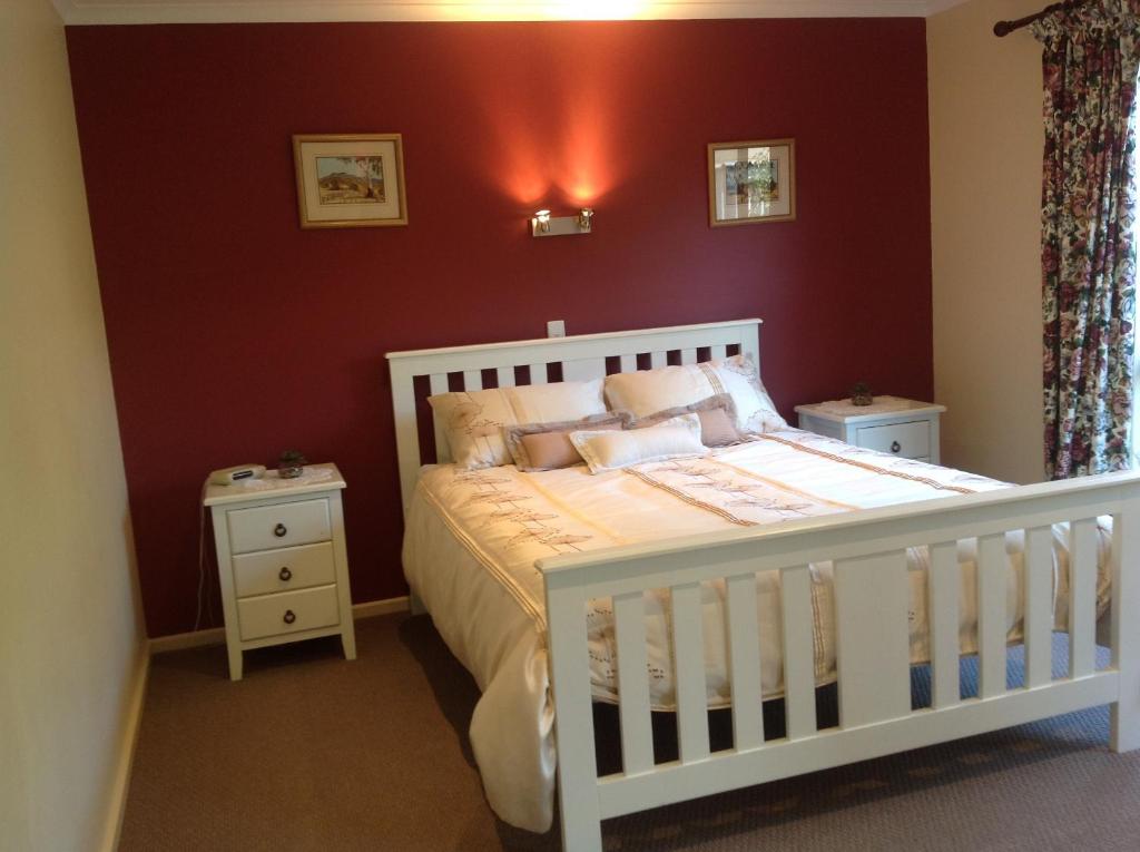 a bedroom with a white crib and a red wall at Breakaway Farmstay in Encounter Bay