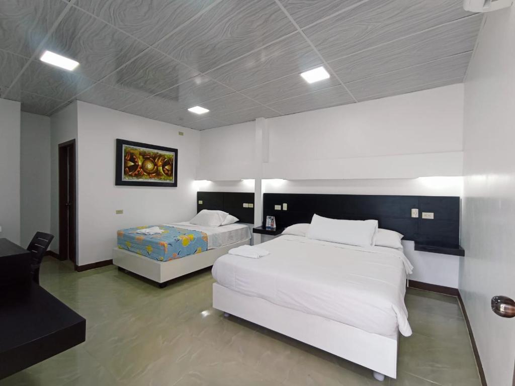 ein großes Schlafzimmer mit 2 Betten und einem Tisch in der Unterkunft Hotel Los Algarrobos in Puerto Baquerizo Moreno