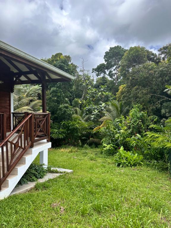 un porche de una casa con césped verde y árboles en gîte de forêt de Guadeloupe, en Petit-Bourg
