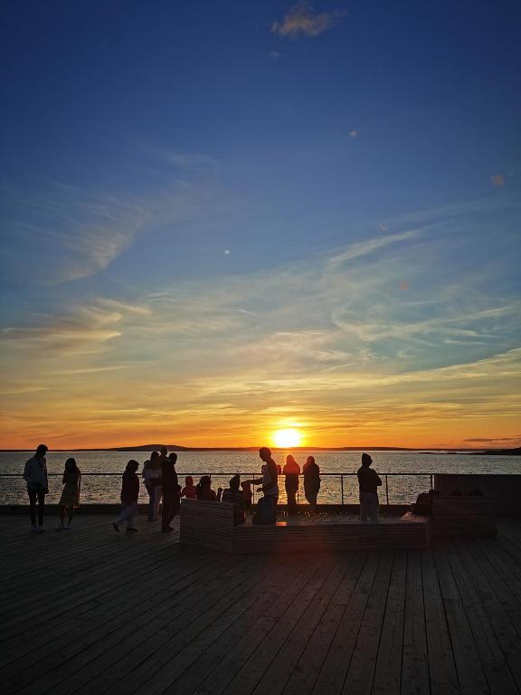 a group of people standing on a pier at sunset at 181 Oceanside Inn in Peggy's Cove