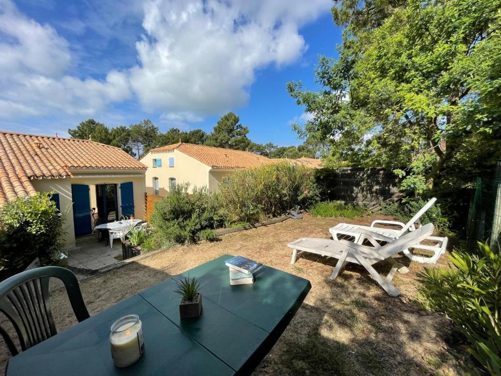 d'une cour avec une table et des chaises. dans l'établissement Maison de vacances avec piscine, terrasse et coin détente en forêt, proche plage! - FR-1-323-486, à Saint-Jean-de-Monts