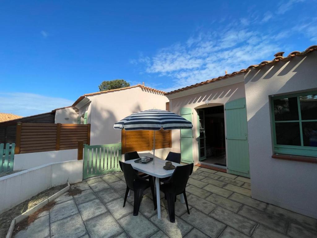 une table et des chaises avec un parasol sur une terrasse dans l'établissement Maison 4-5 pers à Saint Jean de Monts avec piscine, proche plage et forêt - FR-1-323-478, à Saint-Jean-de-Monts