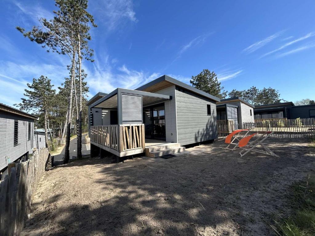 une petite maison avec un porche et une terrasse dans l'établissement Chalet 6 Pers. à Jullouville - Piscine Chauffée, Proche Plage et Commerces - FR-1-361-541, à Saint-Pair-sur-Mer