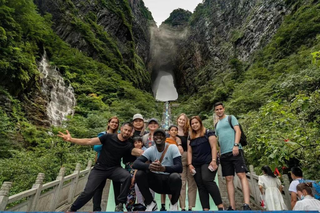 a group of people standing in front of a waterfall at 26 Degrees Inn in Zhangjiajie