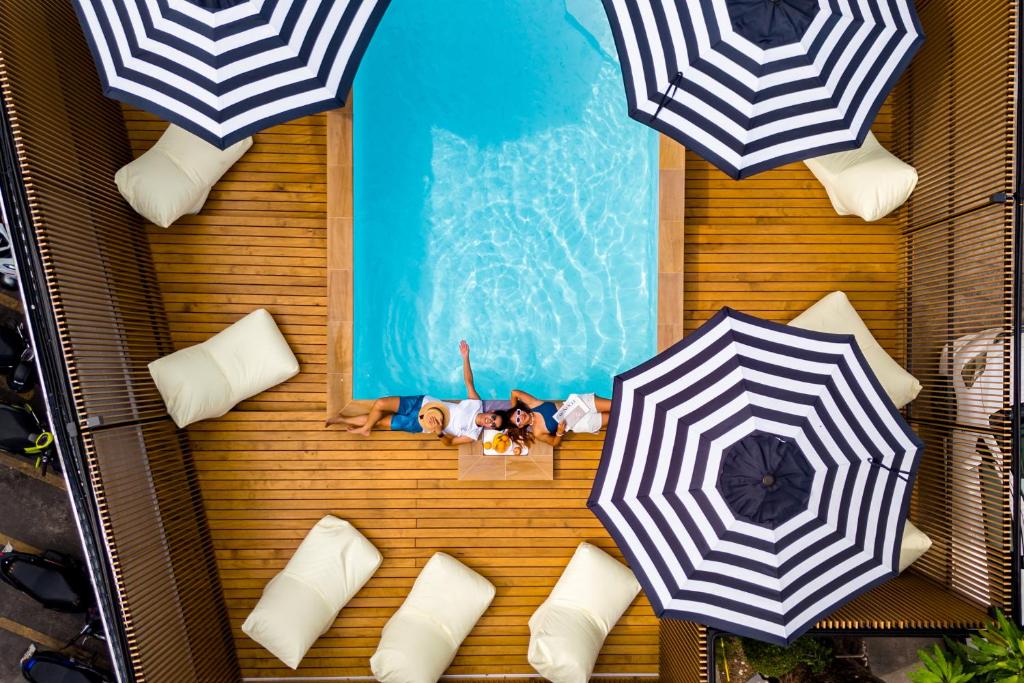 een uitzicht over een zwembad met parasols en kussens bij The Tint At Phuket Town - SHA Plus in Phuket