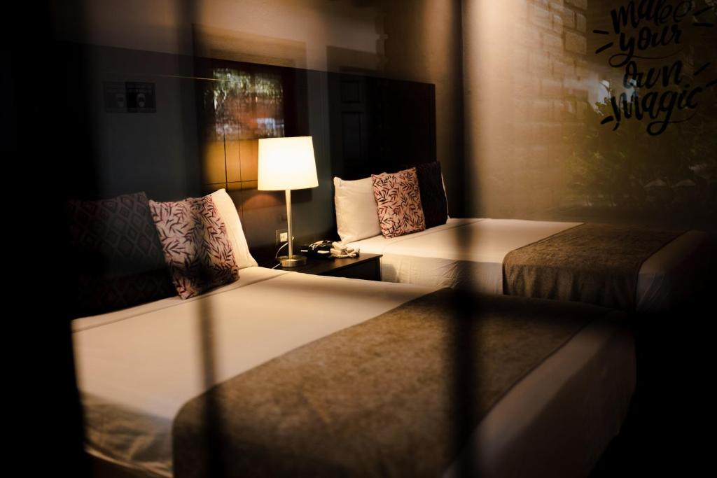 a hotel room with two beds and a lamp at Punto Madero Hotel & Plaza in Mocorito
