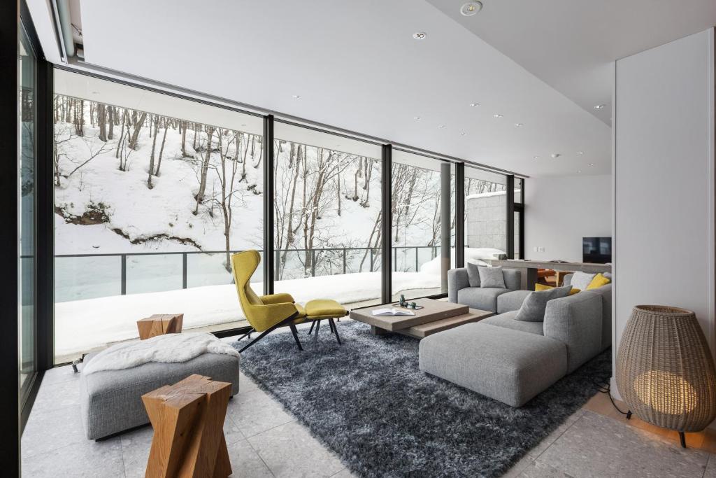 a living room filled with furniture and a large window at YAMAKEI Residences in Niseko