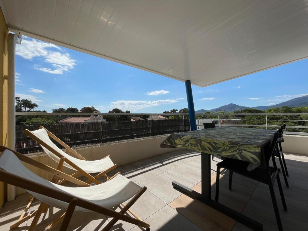 - un balcon avec des chaises, une table et un parasol dans l'établissement Argelès Plage - T3 Neuf avec Clim, 4 Couchages, Parking, Grande Terrasse - FR-1-309-453, à Argelès-sur-Mer