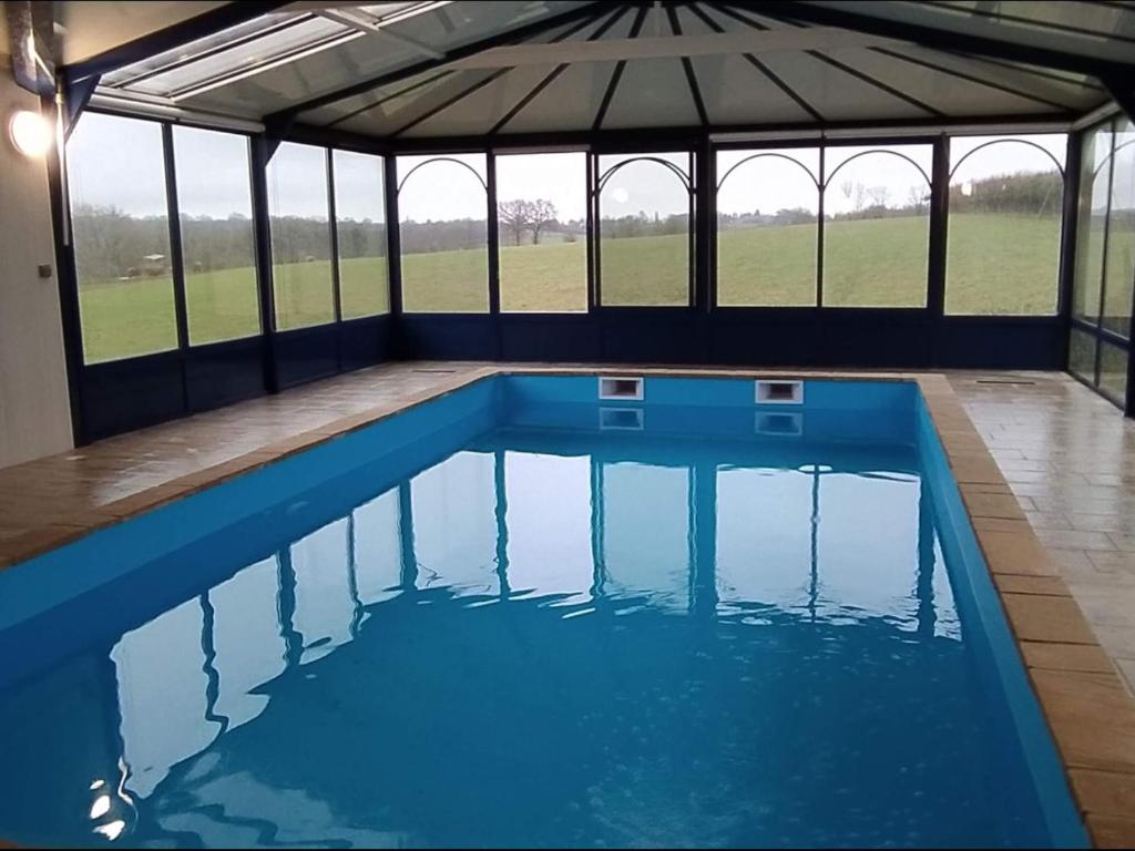 une grande piscine dans un pavillon avec de l'eau bleue dans l'établissement Grande maison avec piscine privée, 7 chambres et vue sur la campagne - FR-1-410-444, à Chemiré-en-Charnie