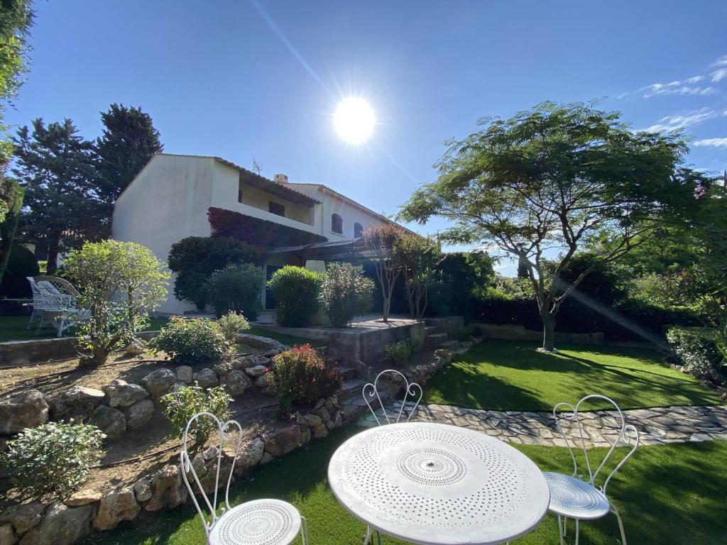 - un jardin avec une table et des chaises en face d'une maison dans l'établissement Villa à Cavalaire-sur-Mer: proche plages, jardin, 3 chambres, balcon, terrain de pétanque - FR-1-100-338, à Cavalaire-sur-Mer