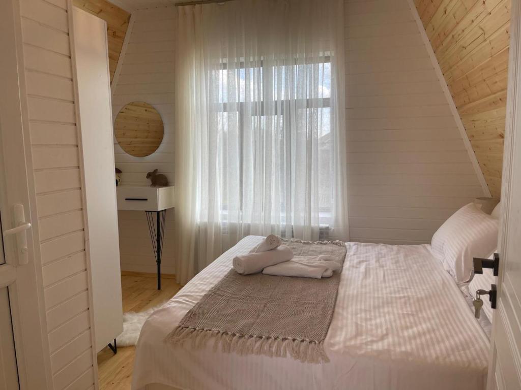 a bedroom with a white bed with a window at Riverfront Chalet Ismayilli in Talıstan