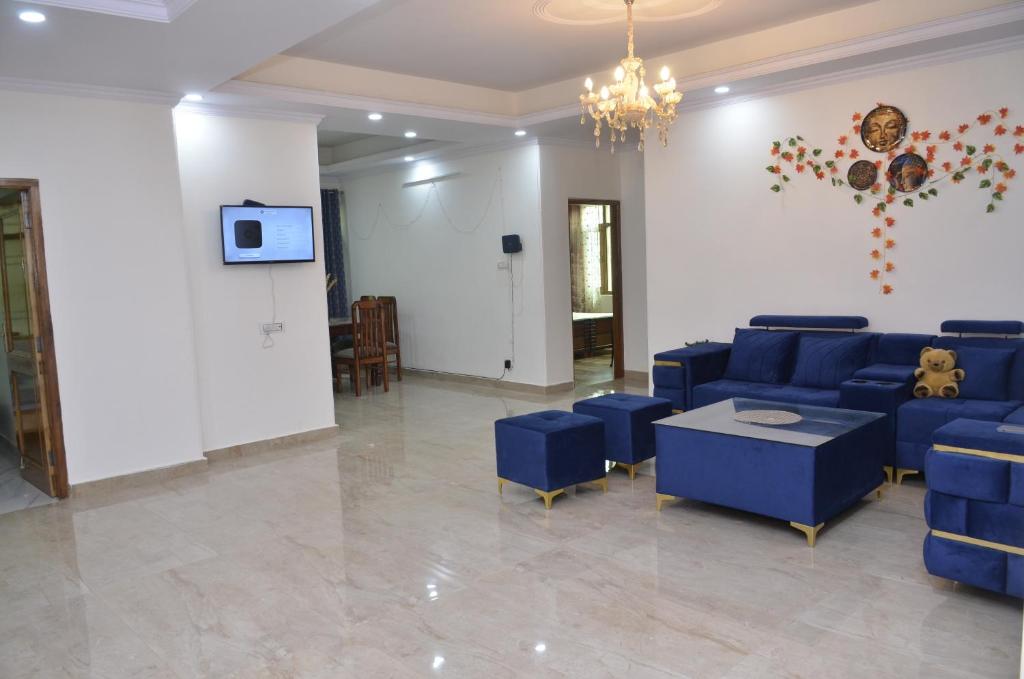 een woonkamer met blauwe banken en een tv bij Family NEST in Shimla