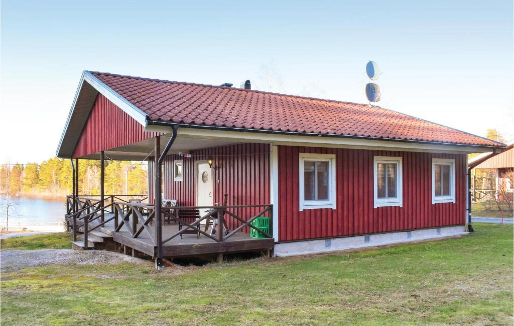 a small red house with a deck on the grass at 3 Bedroom Amazing Home In Holmsjö in Holmsjö