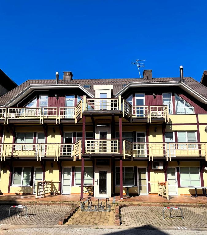 a large apartment building with balconies and a blue sky at Kalno Apartamentai in Juodkrantė