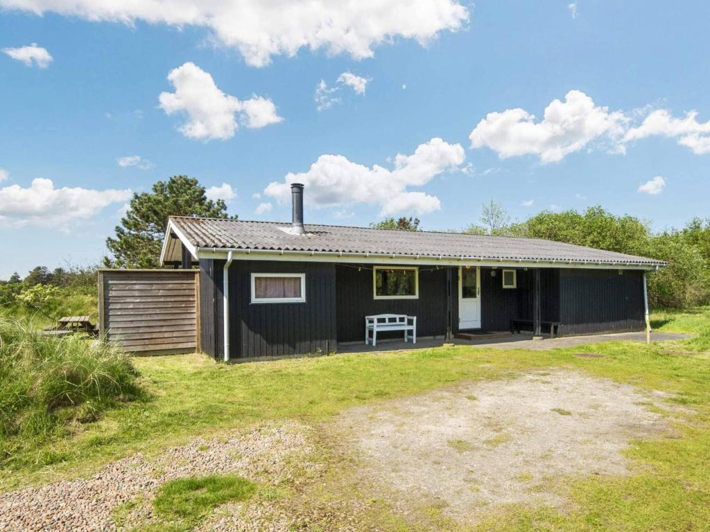 een zwart huis met een bank in een tuin bij 6 person holiday home in Fan in Fanø