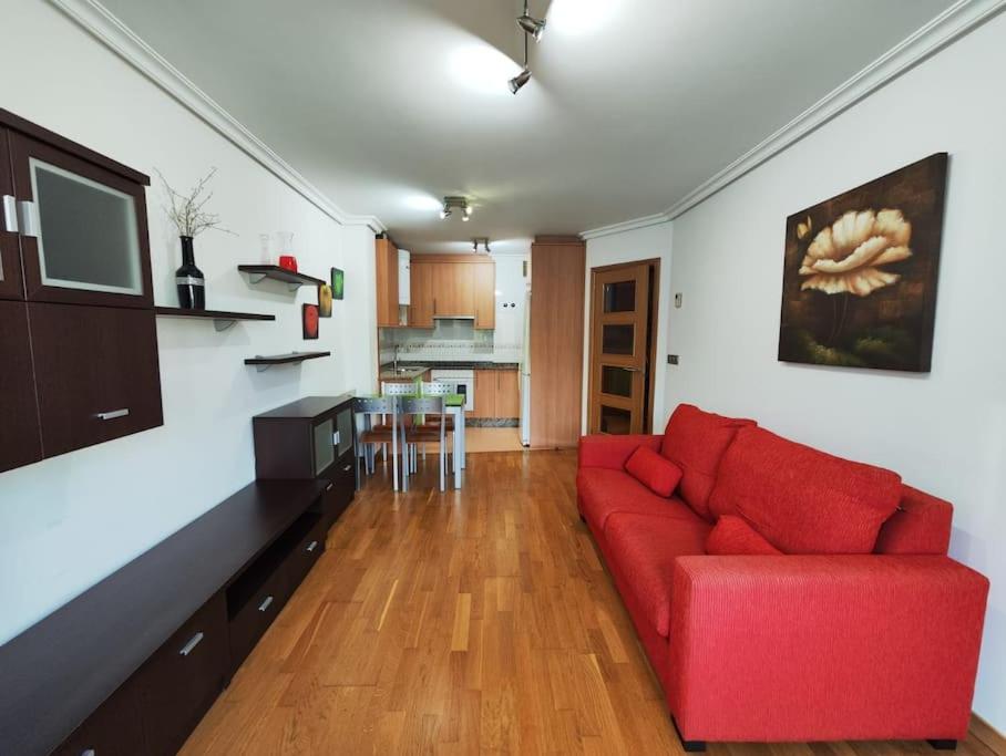 a living room with a red couch and a kitchen at Apartamento centro Nigrán in Nigrán