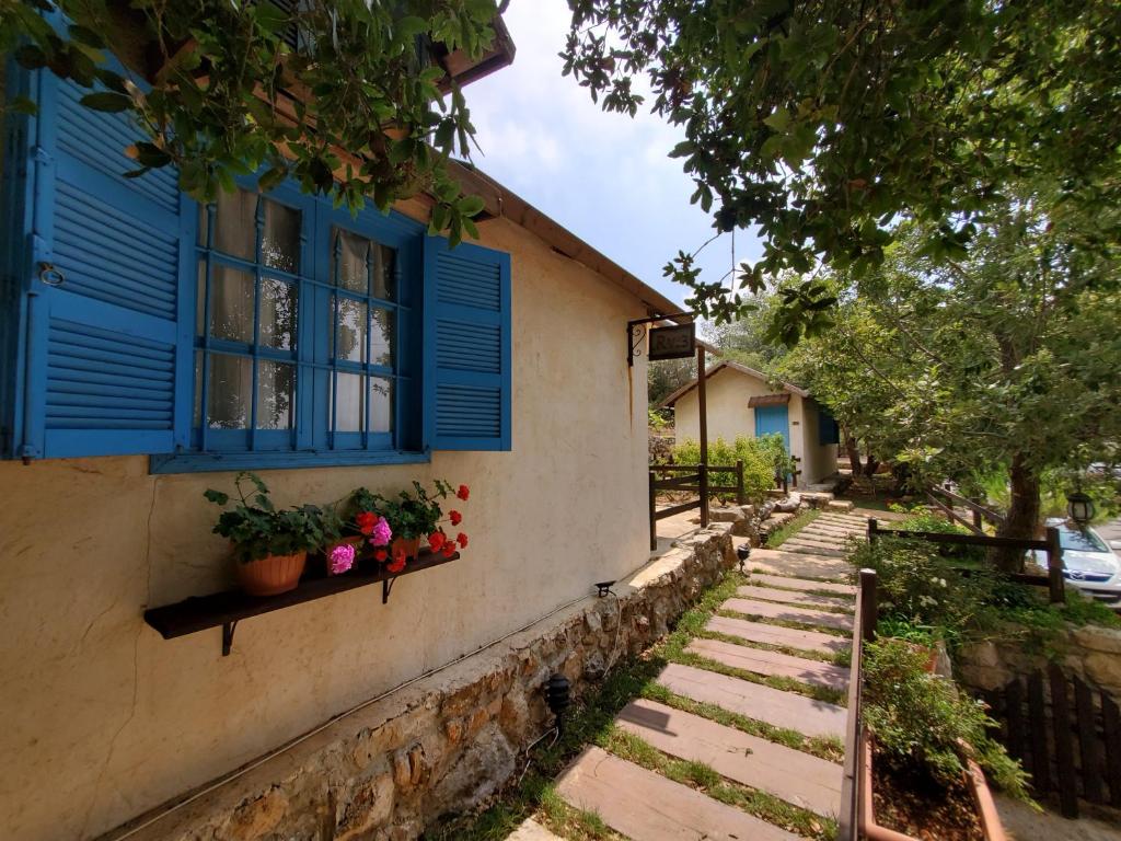 uma casa com uma janela azul e vasos de plantas em Rawa2 Village em Dayr al Qamar