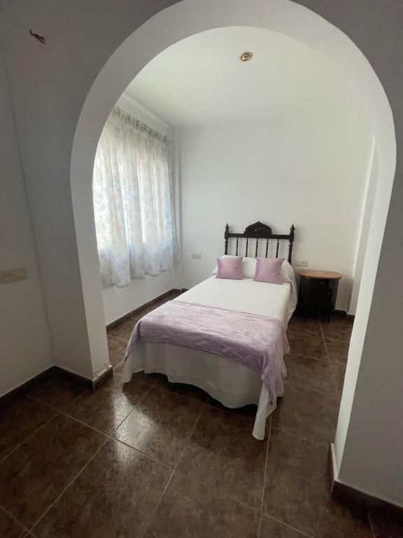 biała sypialnia z łóżkiem z różowymi poduszkami w obiekcie Lo Jardí de Benifallet w mieście Benifallet