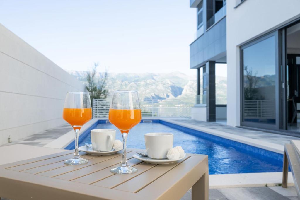 two glasses of wine on a table next to a pool at Villa Velebit - luxury apartment steps away from Adriatic Sea, with private pool and stunning views in Vinjerac
