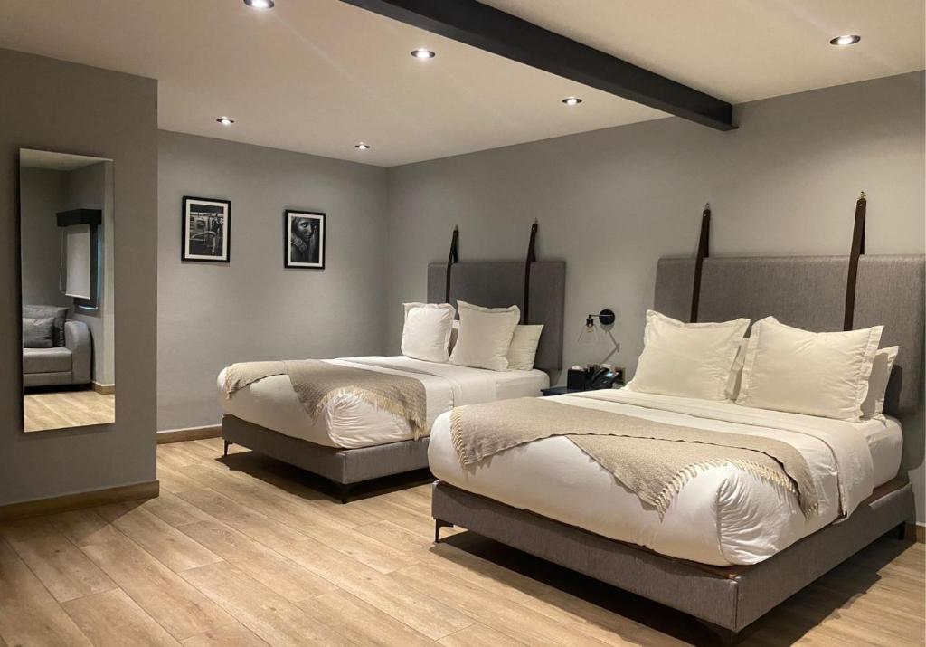 a bedroom with two beds and a mirror at Hotel Verbena in San Miguel de Allende