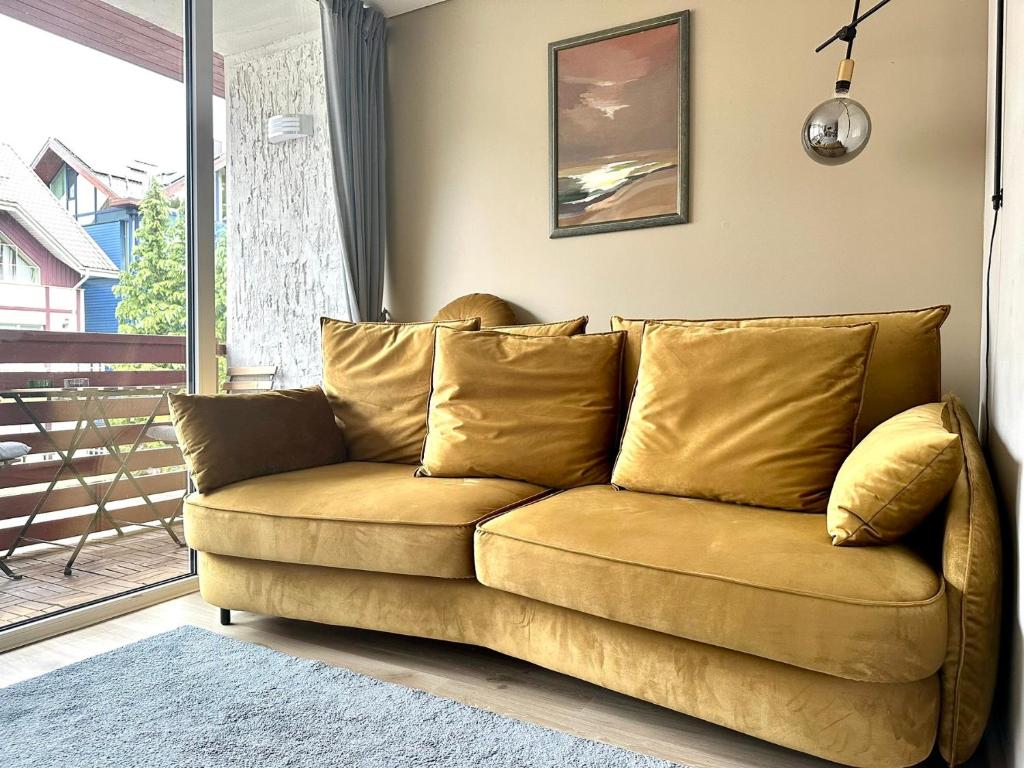 a brown couch in a living room with a window at Studija JV36 in Juodkrantė
