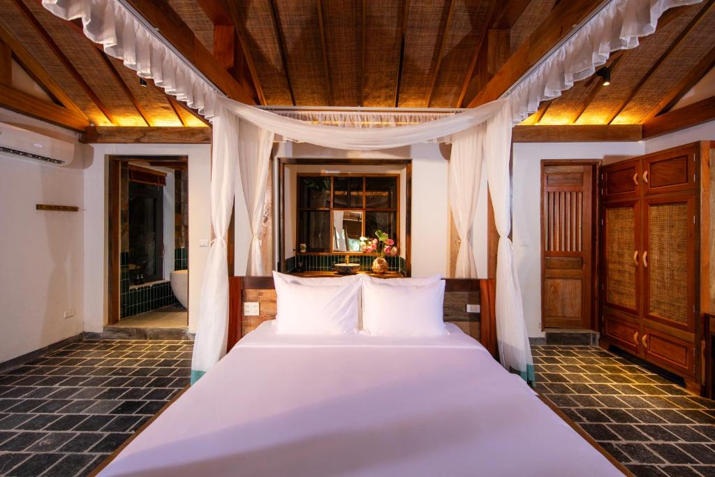 um quarto com uma cama com almofadas brancas em Mua Caves Ecolodge (Hang Mua) em Ninh Binh