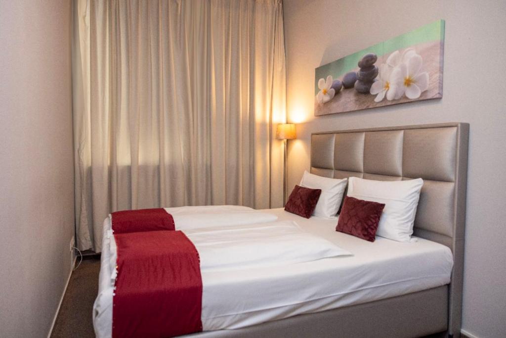 um quarto com uma cama branca e um cobertor vermelho em Twinhof em Hamburgo