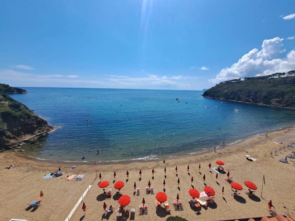 a group of people on a beach with red umbrellas at Elba Travels in Capoliveri