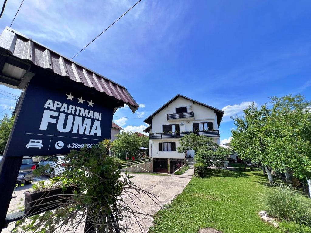 a building with a sign in front of a house at Apartments Fuma in Otočac