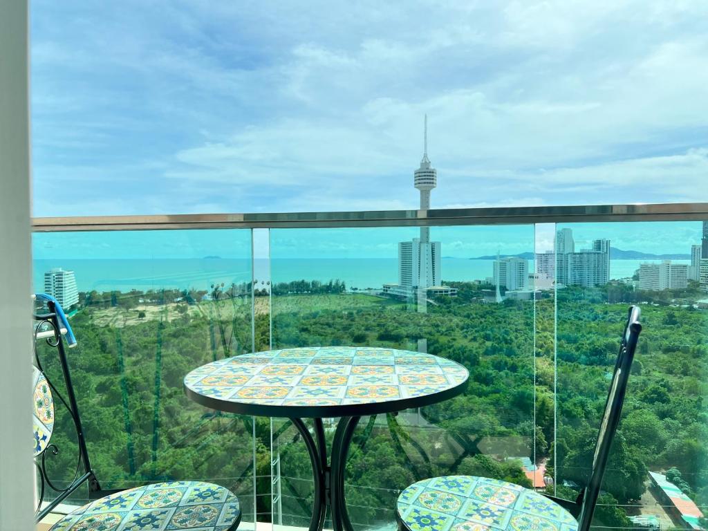 a table and chairs on a balcony with a view of a city at Grande Cariibbean Pattaya by Thita in Pattaya South