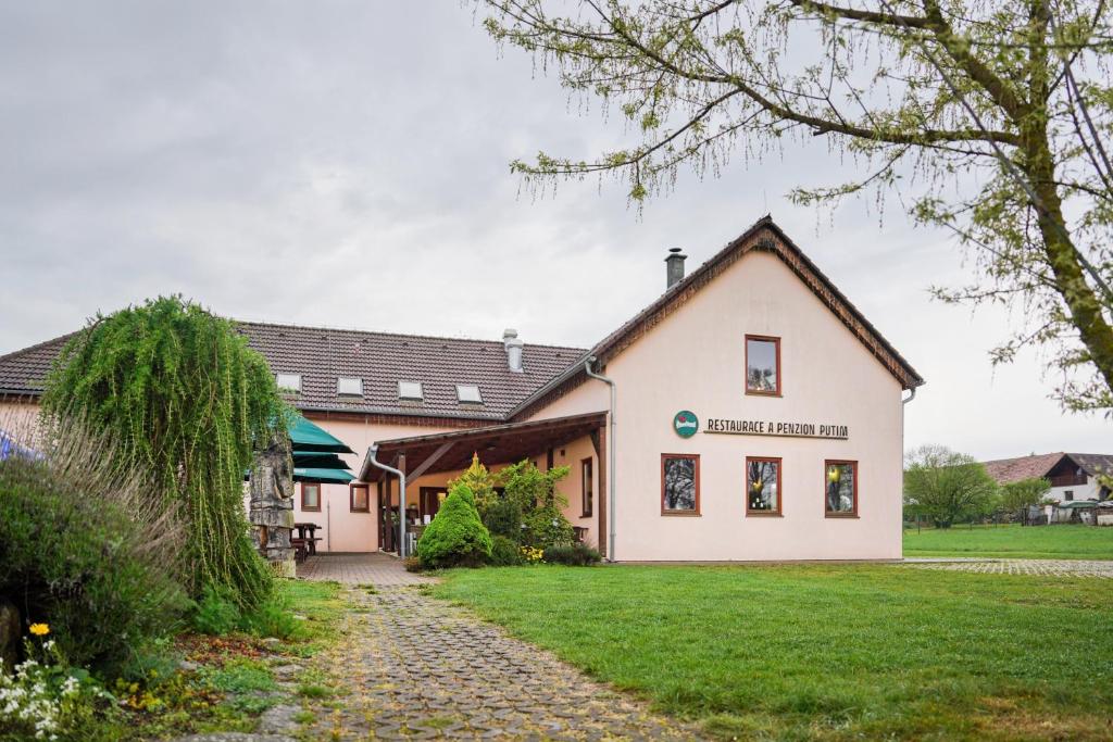 un grand bâtiment blanc avec une pelouse dans l'établissement Penzion Putim, à Putím