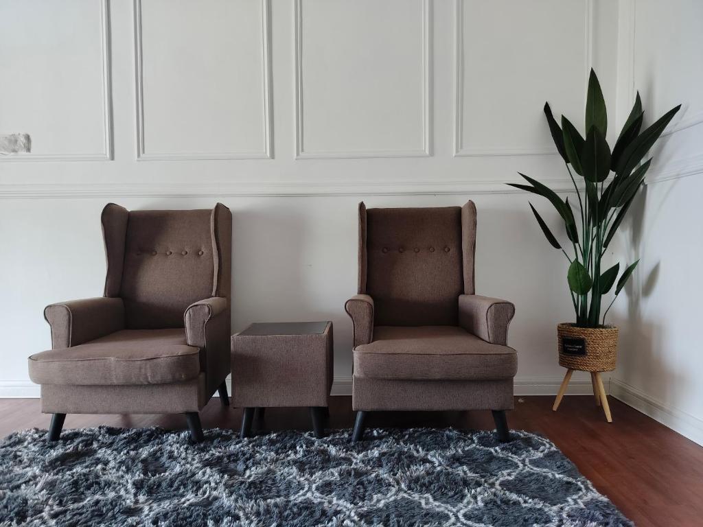 two chairs and a table in a room with a plant at Siti Hawa's Cottage in Banting
