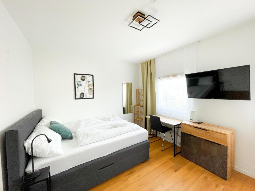 een slaapkamer met een bed, een bureau en een televisie bij StayHere City Studio NB 18 - contactless Self-Check-IN in Graz