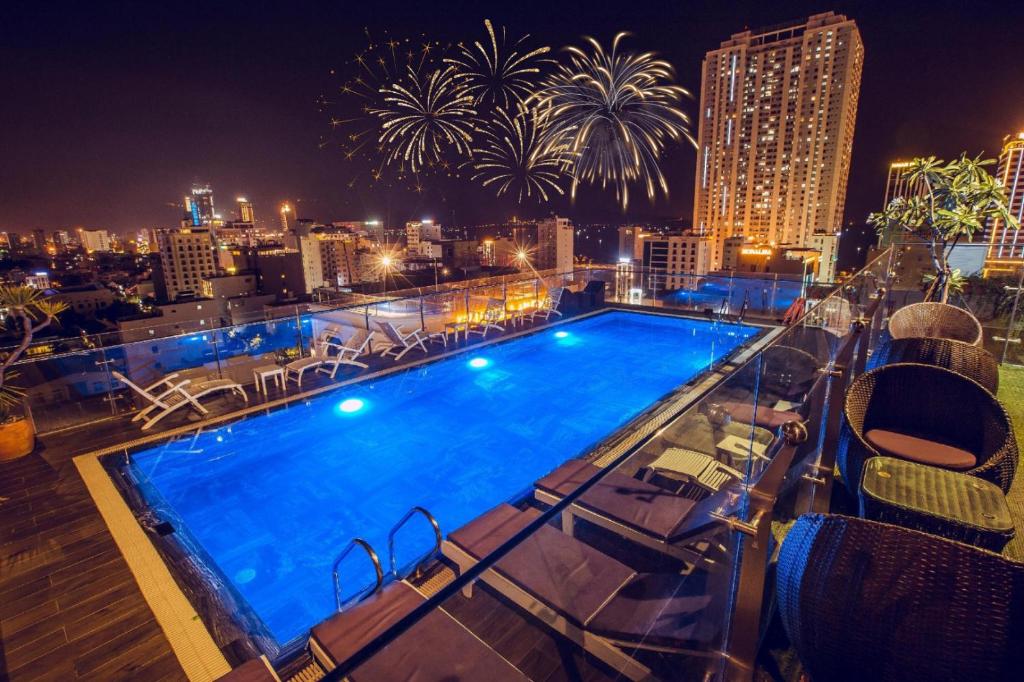 ein Pool auf dem Dach eines Gebäudes mit Feuerwerk in der Unterkunft Aria Grand Hotel & Spa in Đà Nẵng