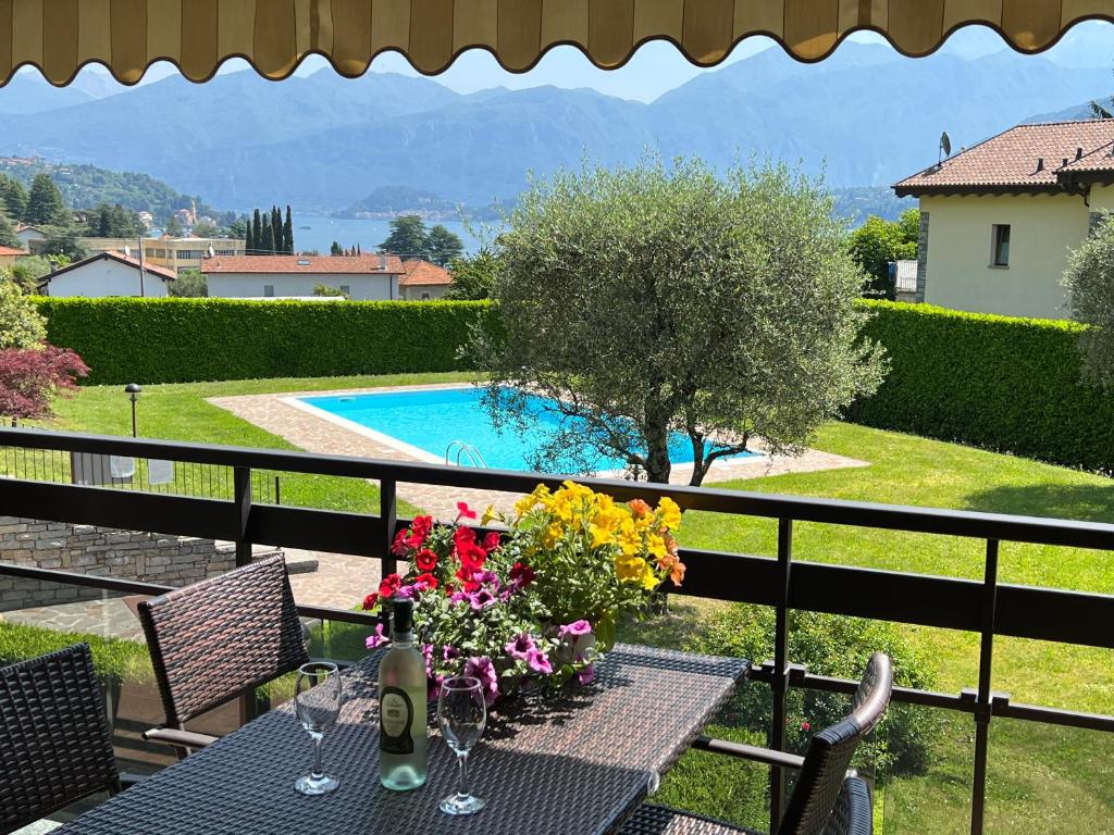 a table with flowers on top of a balcony with a pool at Alba sul Lago in Lenno