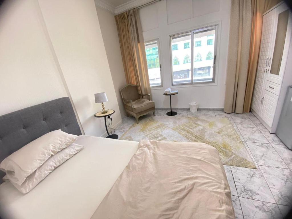 アブダビにあるDinar stayのベッドルーム1室(ベッド1台、椅子、窓付)