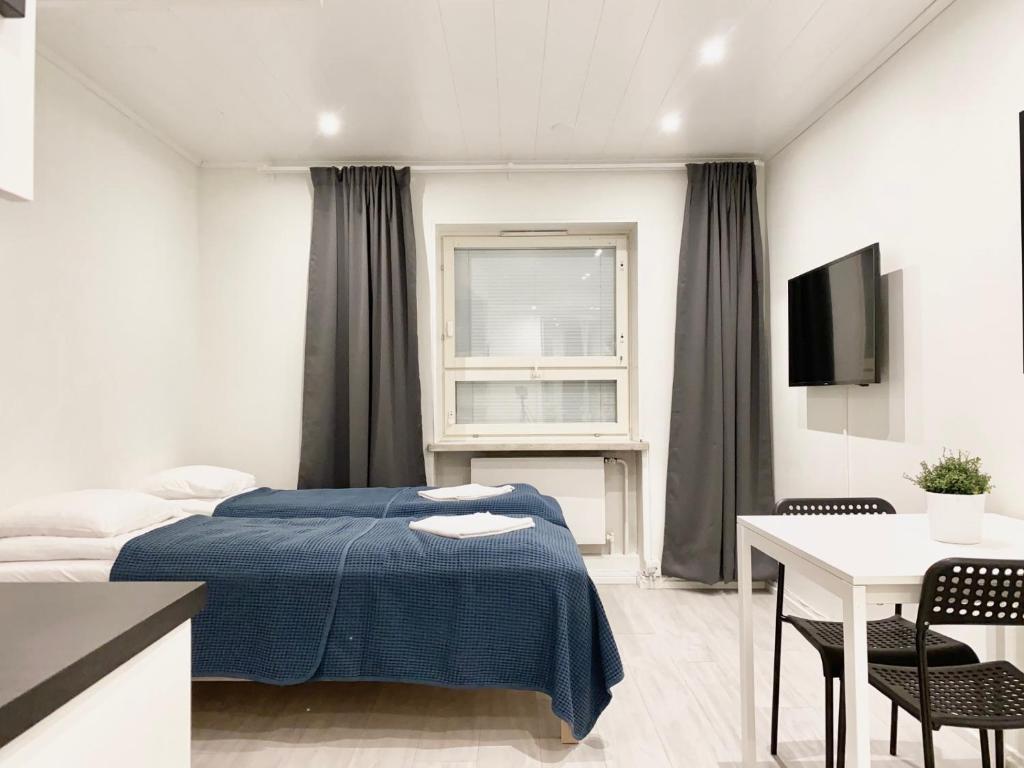 een slaapkamer met een bed, een tafel en een televisie bij City Center Studio Pori in Pori