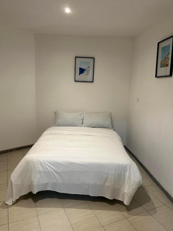 Ce lit se trouve dans une chambre blanche dotée d'un couvre-lit blanc. dans l'établissement TOP appartement centre ville, à Valenciennes